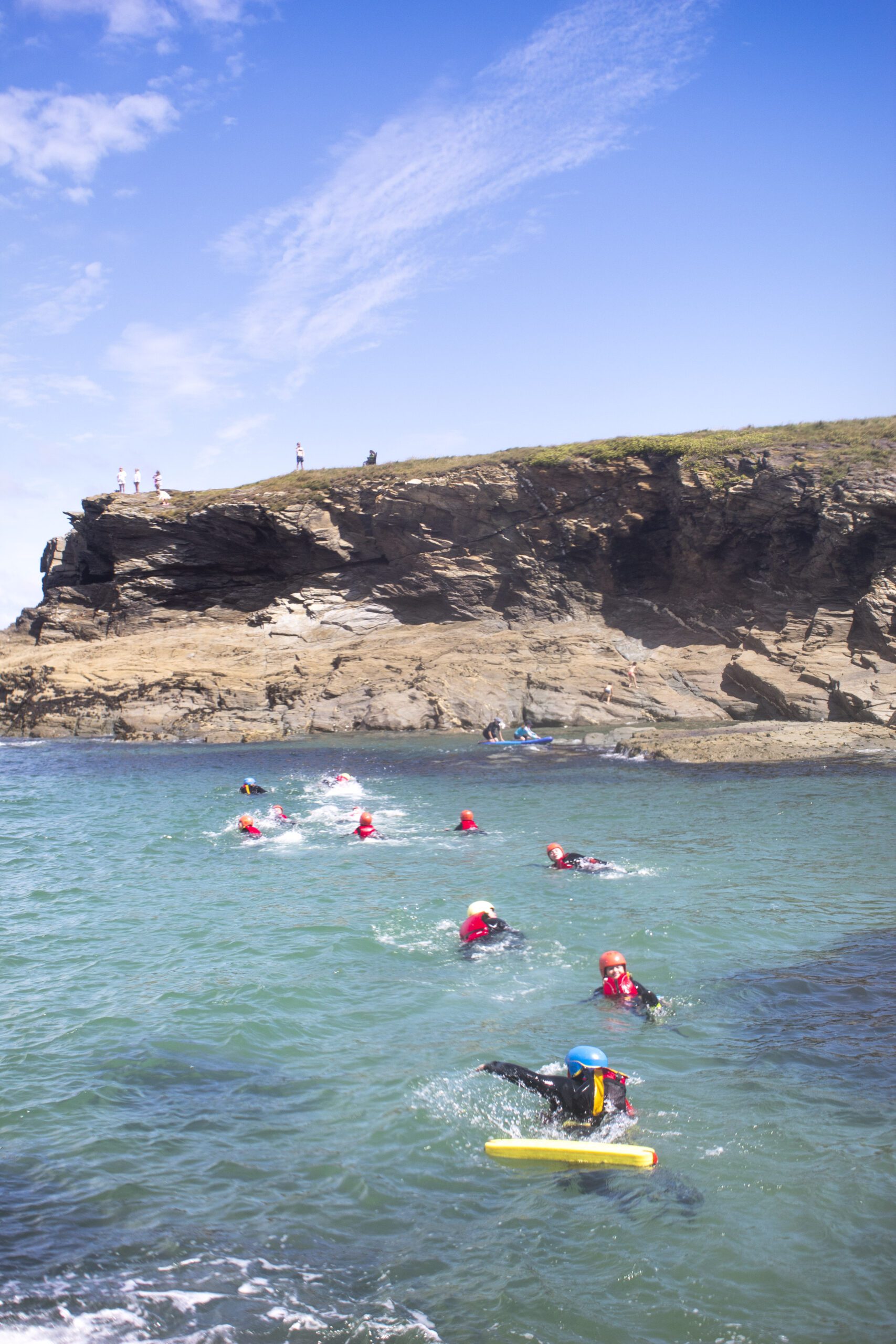 Coasteering group swimming beneath the cliffs of North Cornwal